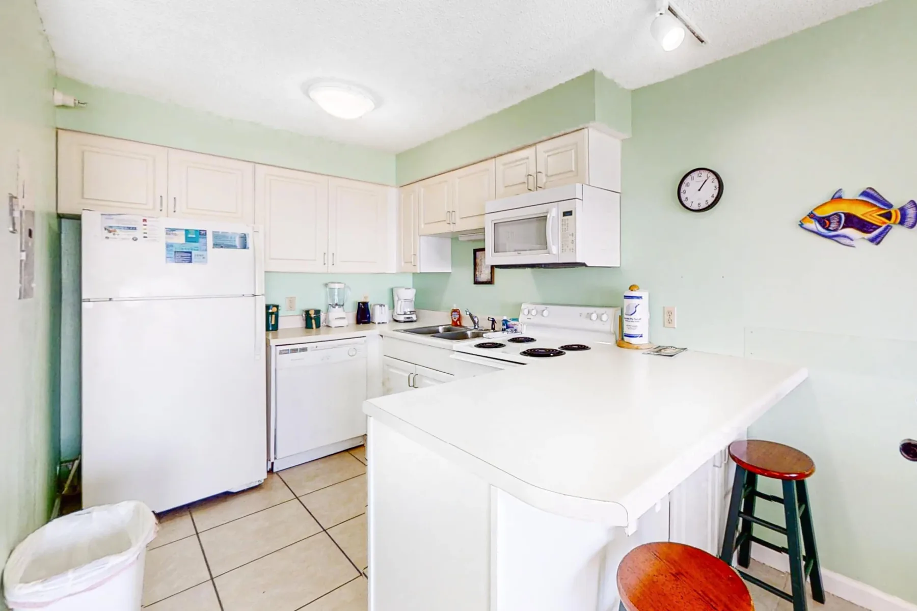 A bright kitchen with white cabinets, appliances, and a central island.