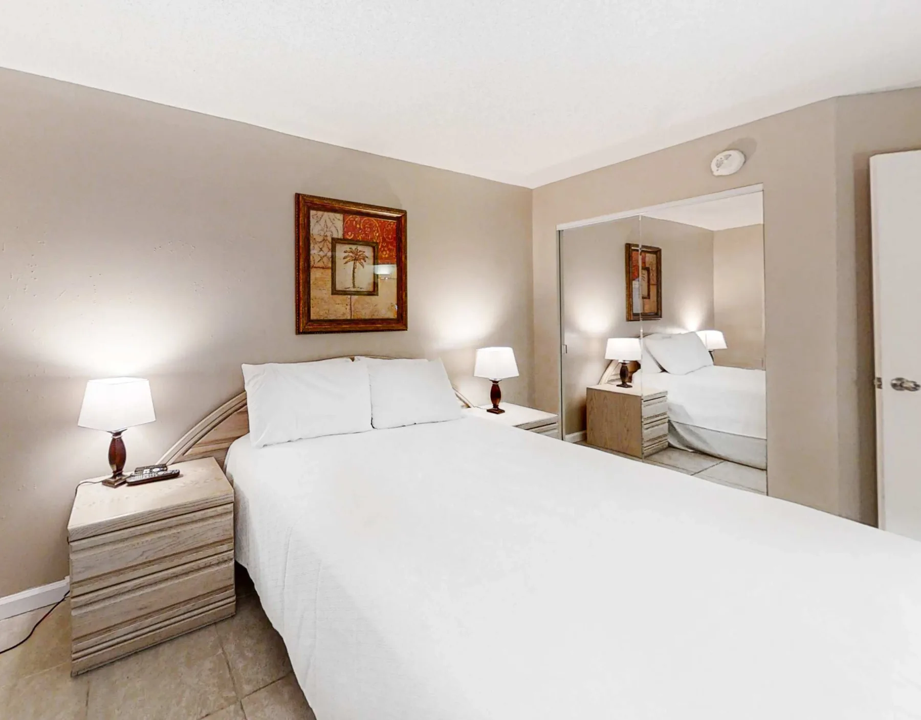 A bedroom with a bed, matching bedside tables, and framed wall art.