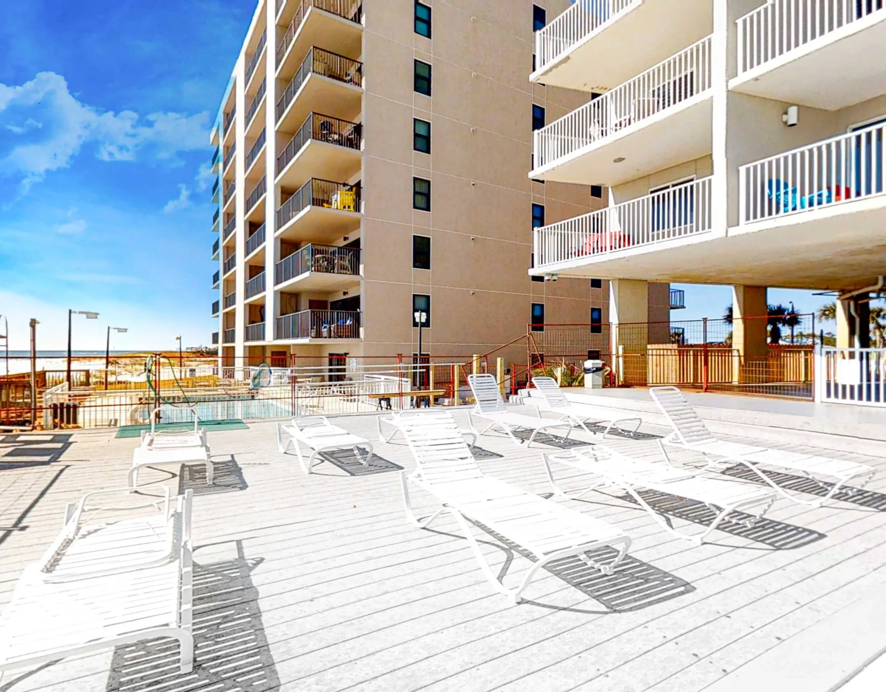 Shared amenity: Poolside deck with lounge seating beside a multi-story building.