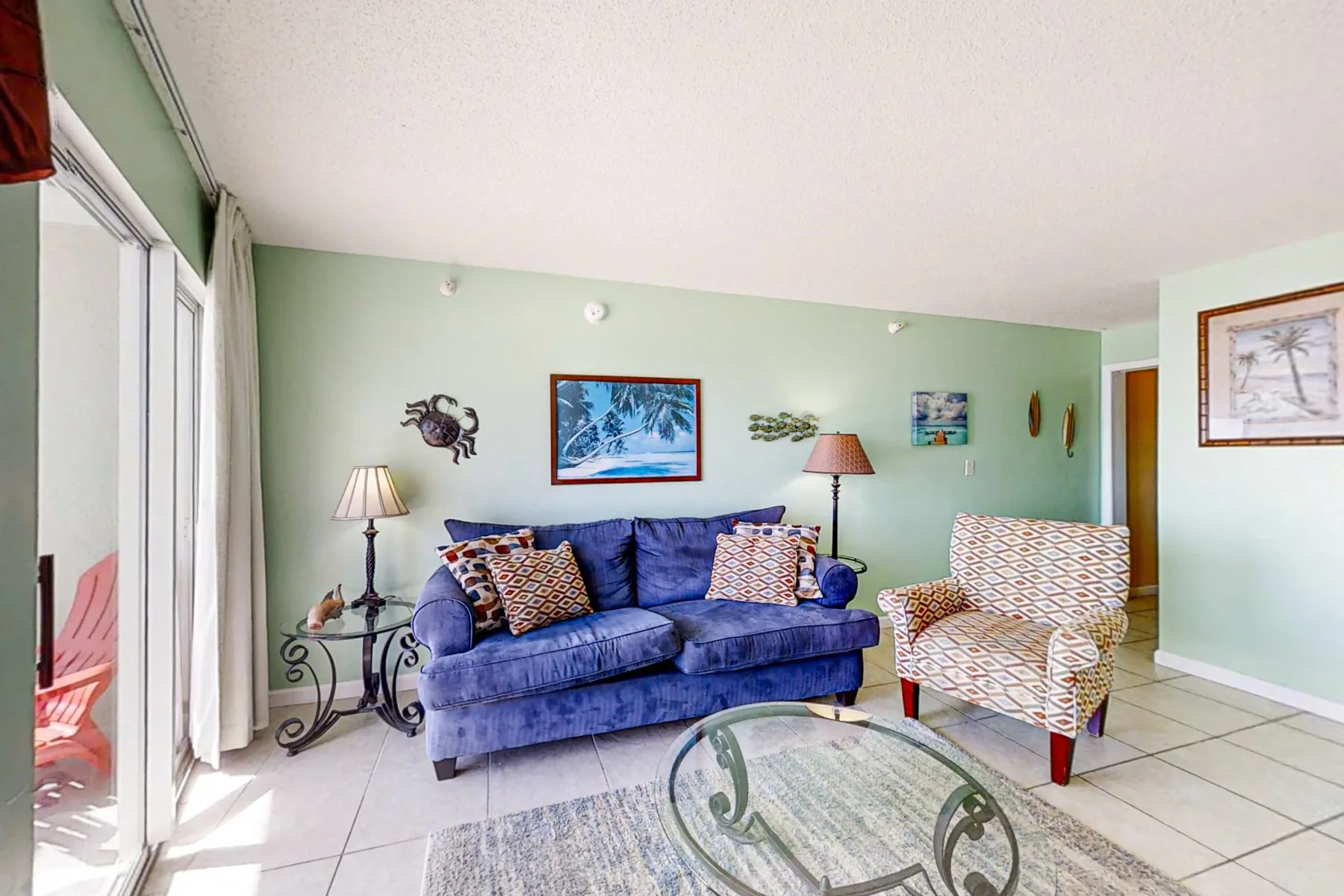 Living room with blue seating, patterned cushions, and a glass coffee table.
