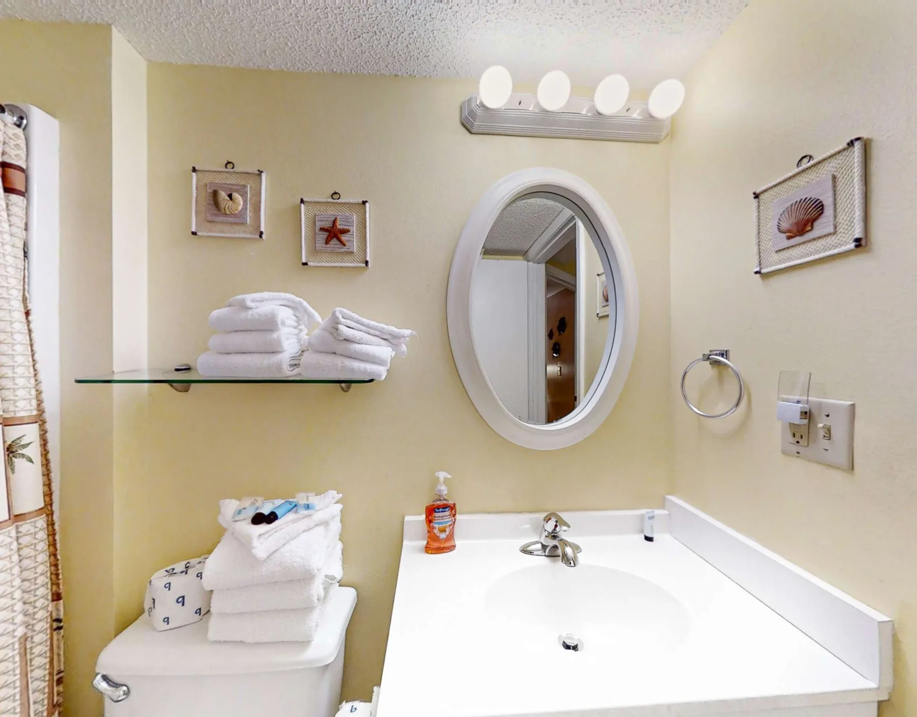 A bathroom vanity with a sink, oval mirror, and towels on a shelf.