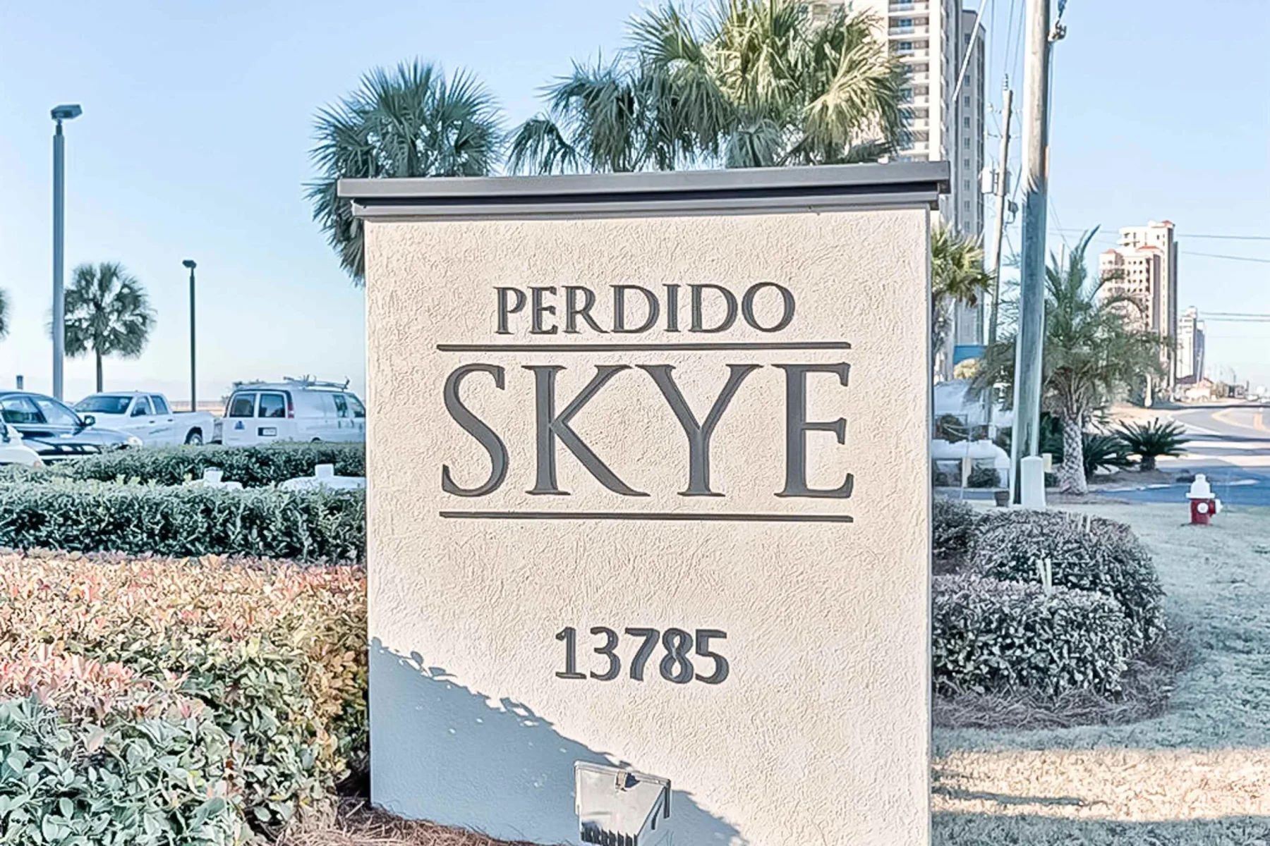 Shared amenity: A roadside sign for Perdido Skye stands among landscaped shrubs and palm trees.
