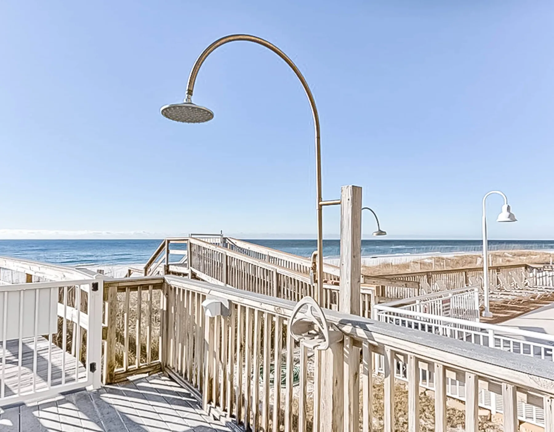 Shared amenity: Outdoor deck with wooden railings and shower fixtures overlooking the ocean.