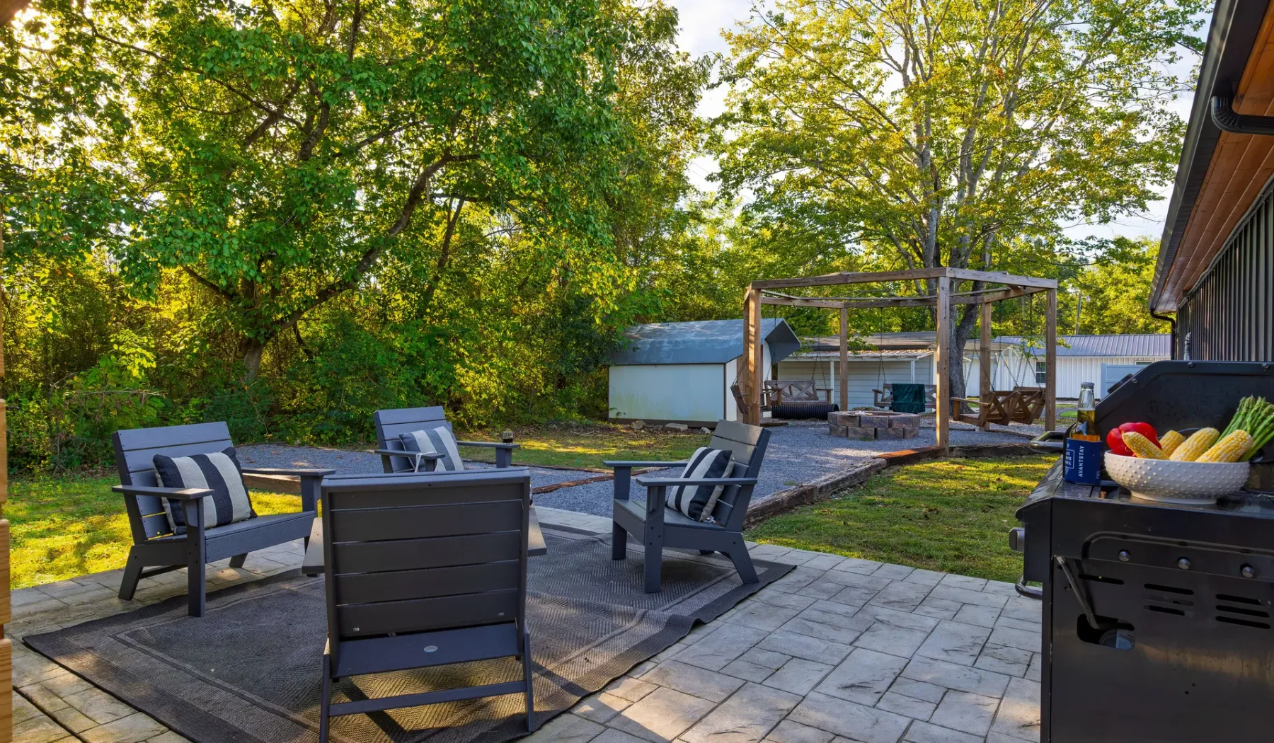 An outdoor patio with seating overlooks a yard and a covered pool area.