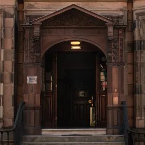 Espacio representativo del hotel: Entrada de un edificio de piedra con un arco tallado sobre la puerta oscura.