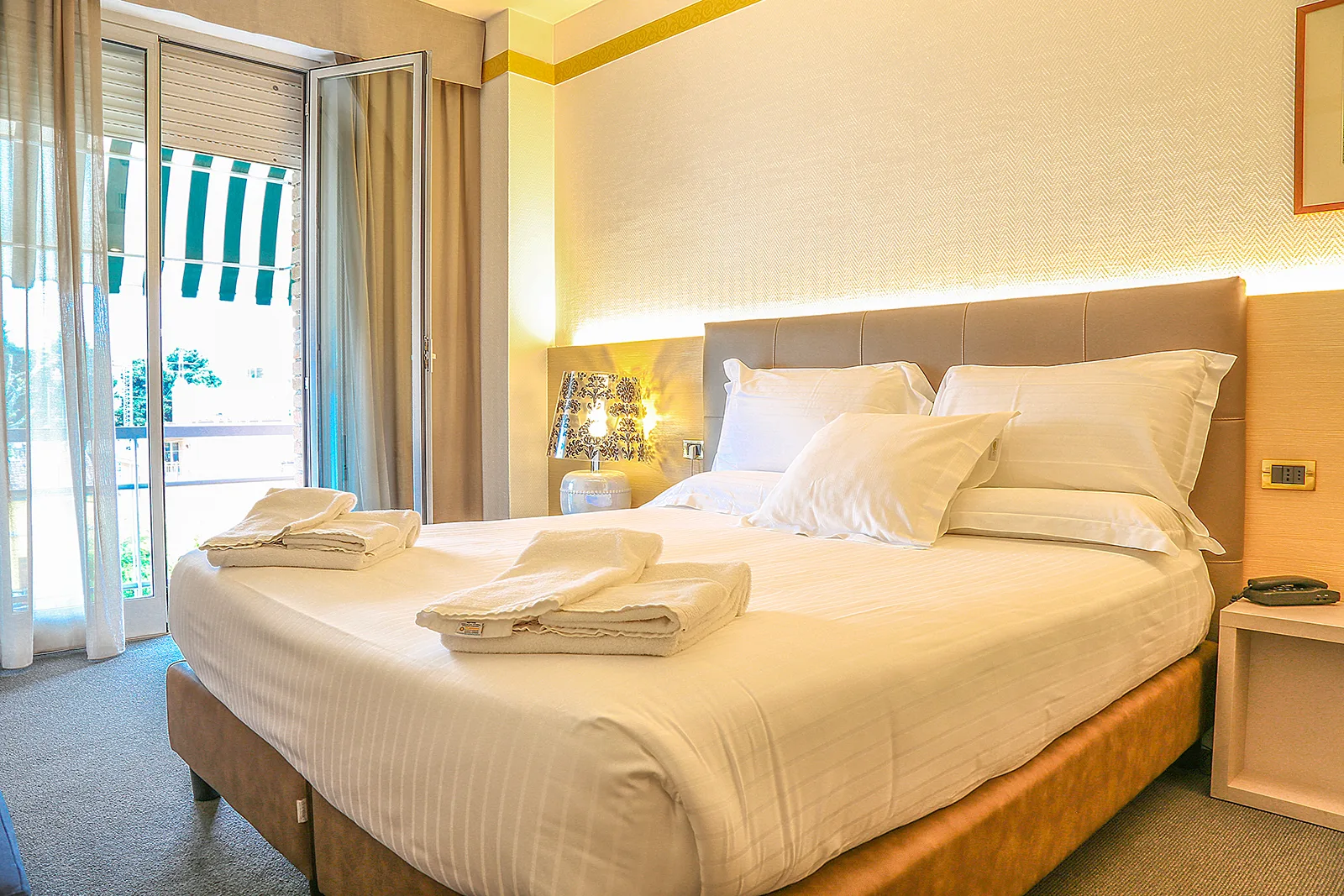 Representative hotel space: A bedroom with a large bed and an open balcony door.