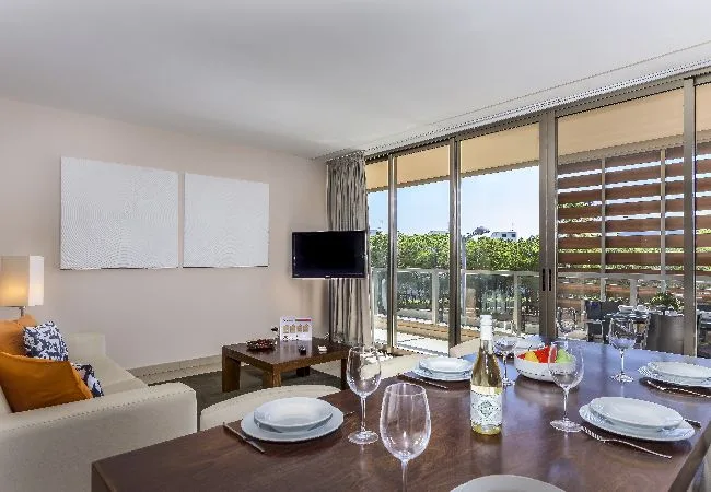 Una luminosa sala de estar y comedor se abre a un balcón mediante grandes puertas de cristal.