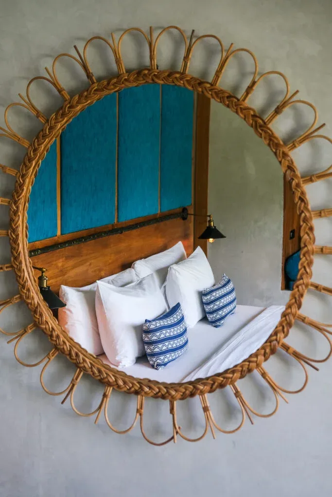 Espacio representativo del hotel: Dormitorio con ropa de cama blanca y un gran espejo circular tejido sobre la cama.