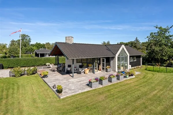 A single-story house with a broad wooden deck and garden seating.