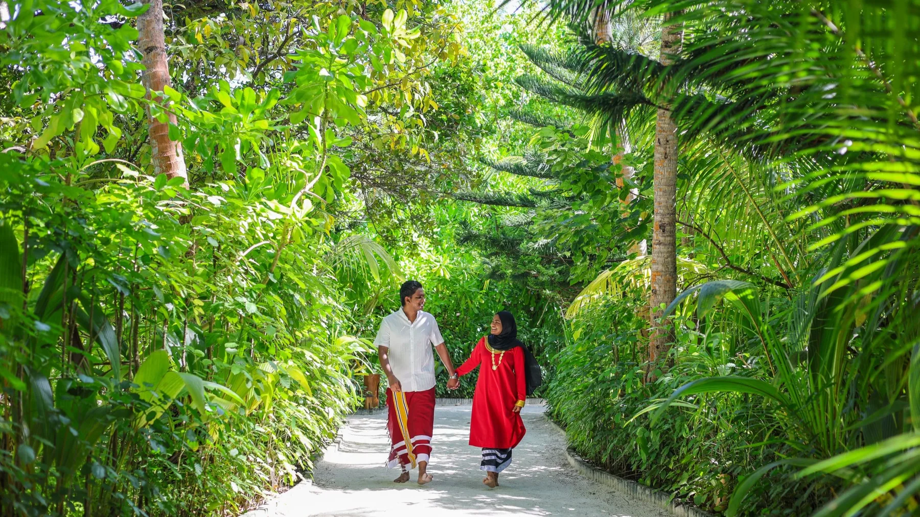 Representative hotel space: A garden path winds through dense tropical greenery as two people walk along it.