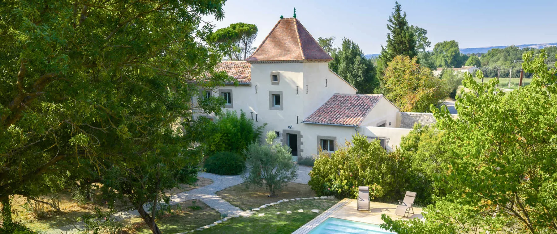 Representative hotel space: A white building with a tiled roof stands beside a garden and swimming pool.