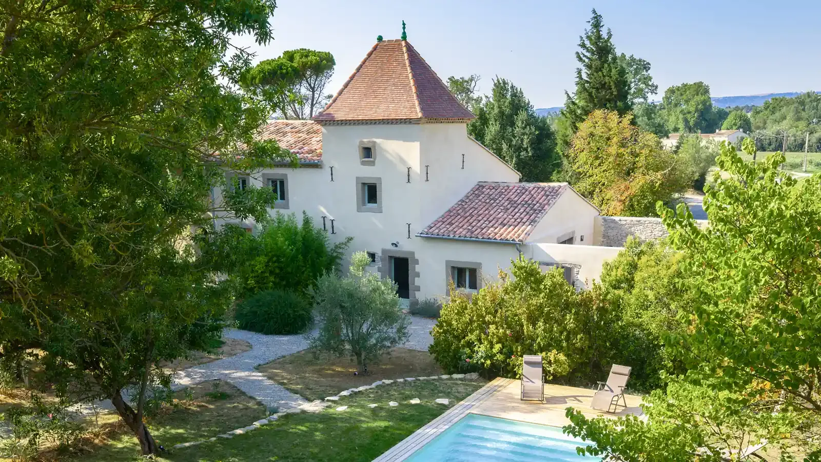 Representative hotel space: A white building with a tiled roof stands beside a garden and swimming pool.