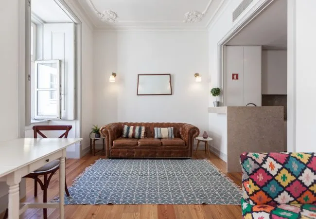 Una sala luminosa con un sofá marrón y una alfombra estampada.