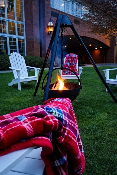 Espacio representativo del hotel: Una zona de estar al aire libre con un brasero encendido y mantas de cuadros rojos.