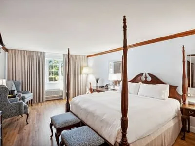 Espacio representativo del hotel: Un dormitorio con una cama grande, asientos tapizados y ventanas altas con cortinas.