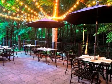 Espacio representativo del hotel: Un patio exterior con mesas bajo guirnaldas de luces y sombrillas.