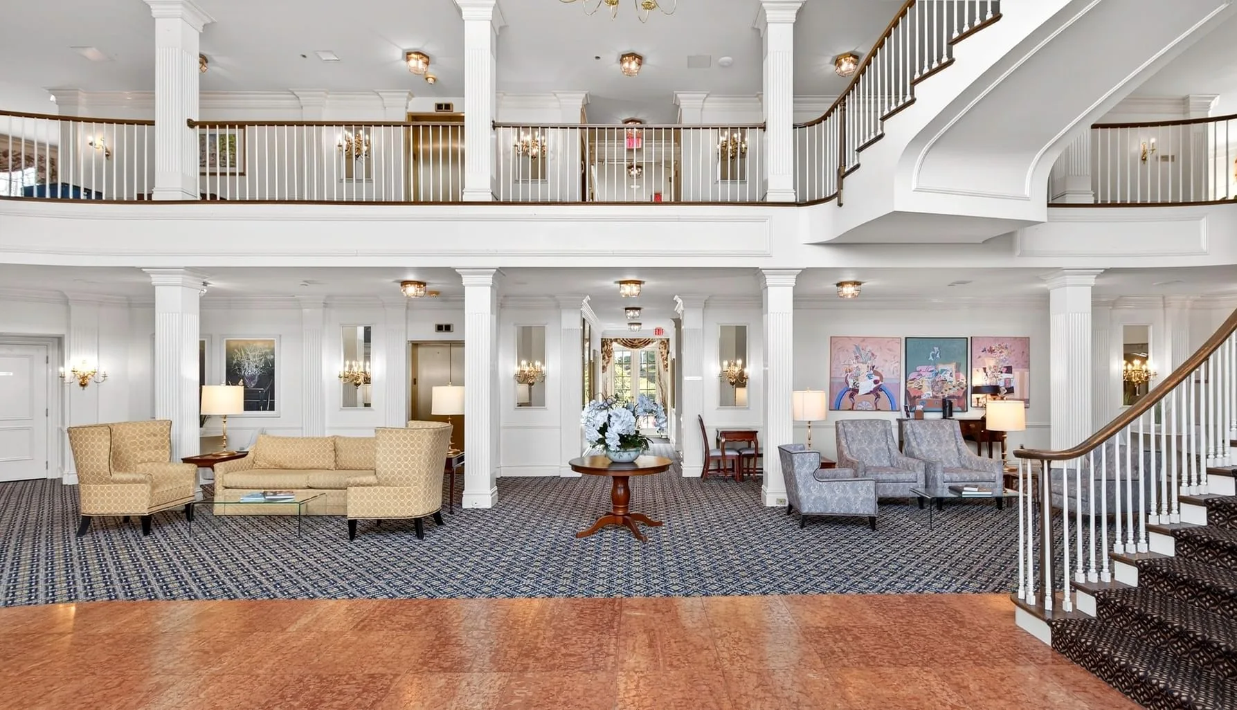 Espacio representativo del hotel: Vestíbulo de hotel con zonas de asientos bajo una escalera y un balcón superior.