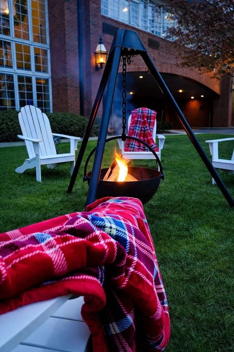 Espacio representativo del hotel: Zona de estar al aire libre con una fogata encendida y mantas de cuadros rojos.