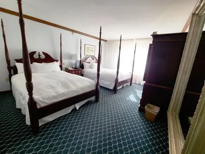 Espacio representativo del hotel: Un dormitorio con dos camas, un armario y suelo estampado.