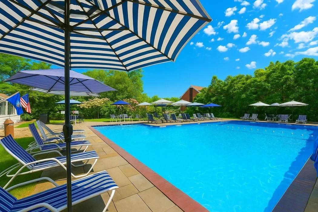 Espacio representativo del hotel: Una piscina al aire libre está rodeada de asientos reclinables y sombrillas a rayas.