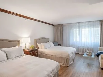 Espacio representativo del hotel: Dormitorio de hotel con dos camas y una ventana grande con cortinas.