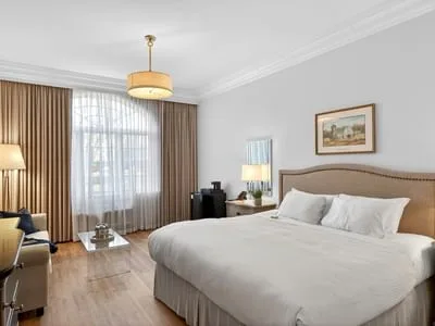 Espacio representativo del hotel: Un dormitorio con una cama grande junto a una ventana con cortinas.