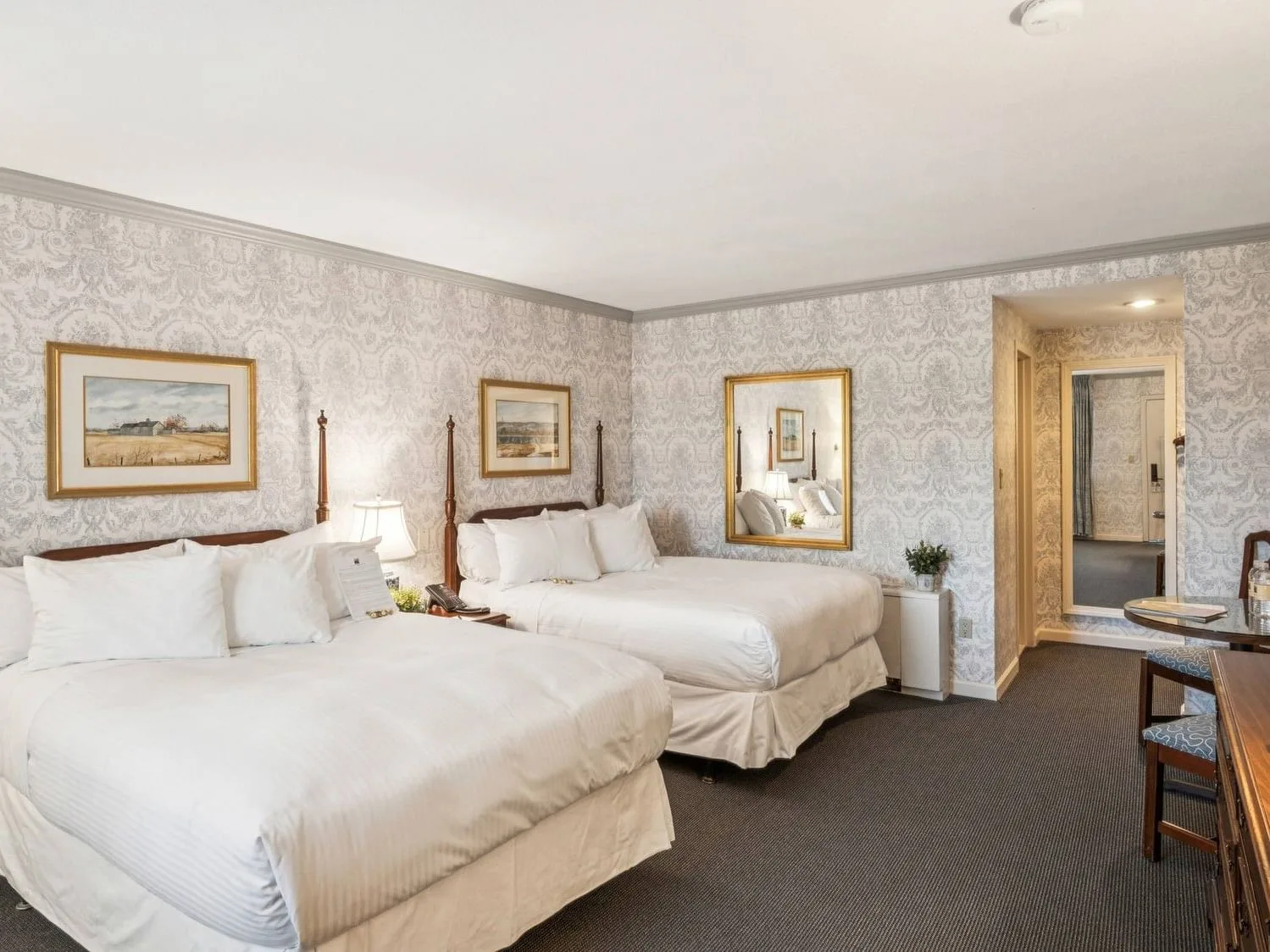 Espacio representativo del hotel: Un dormitorio con dos camas, papel tapiz estampado y cuadros enmarcados.