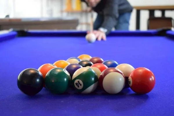 Espacio representativo del hotel: Una mesa de billar con bolas de colores agrupadas y una persona preparándose para tirar.