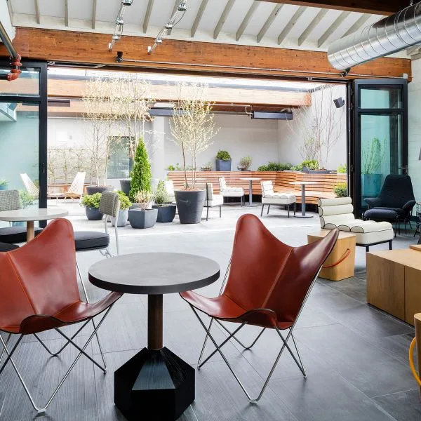 Espacio representativo del hotel: Un salón luminoso con asientos alrededor de una mesa y un patio abierto al fondo.