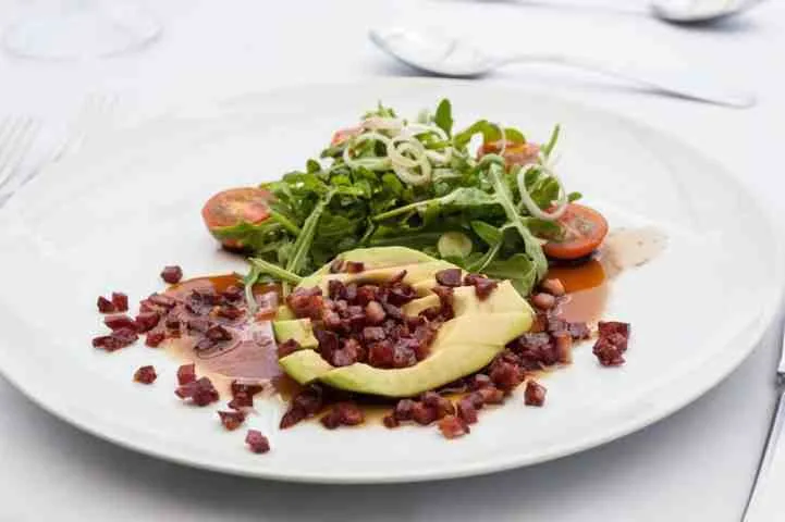 Representative hotel space: A plated salad with greens, avocado, tomatoes, and diced toppings.