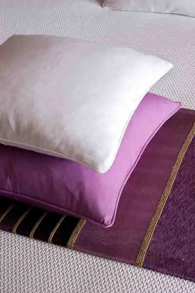 Representative hotel space: A bed with layered pillows and a purple striped cover.