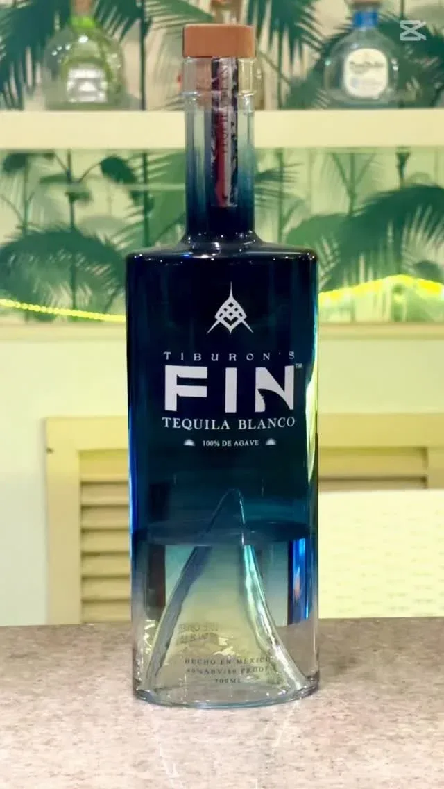 Espacio representativo del hotel: Una botella de tequila está sobre un mostrador frente a un escaparate decorativo.