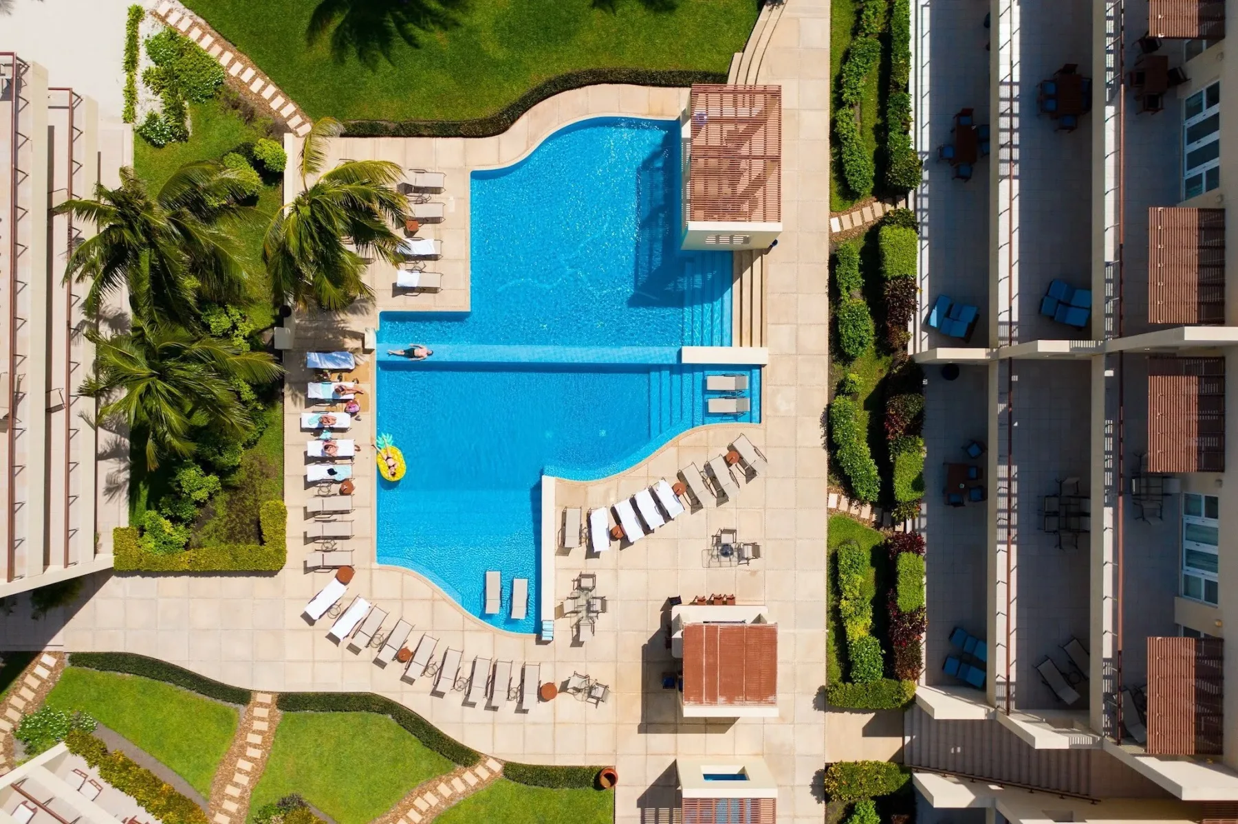 Espacio representativo del hotel: Una piscina al aire libre está rodeada de tumbonas y jardines.