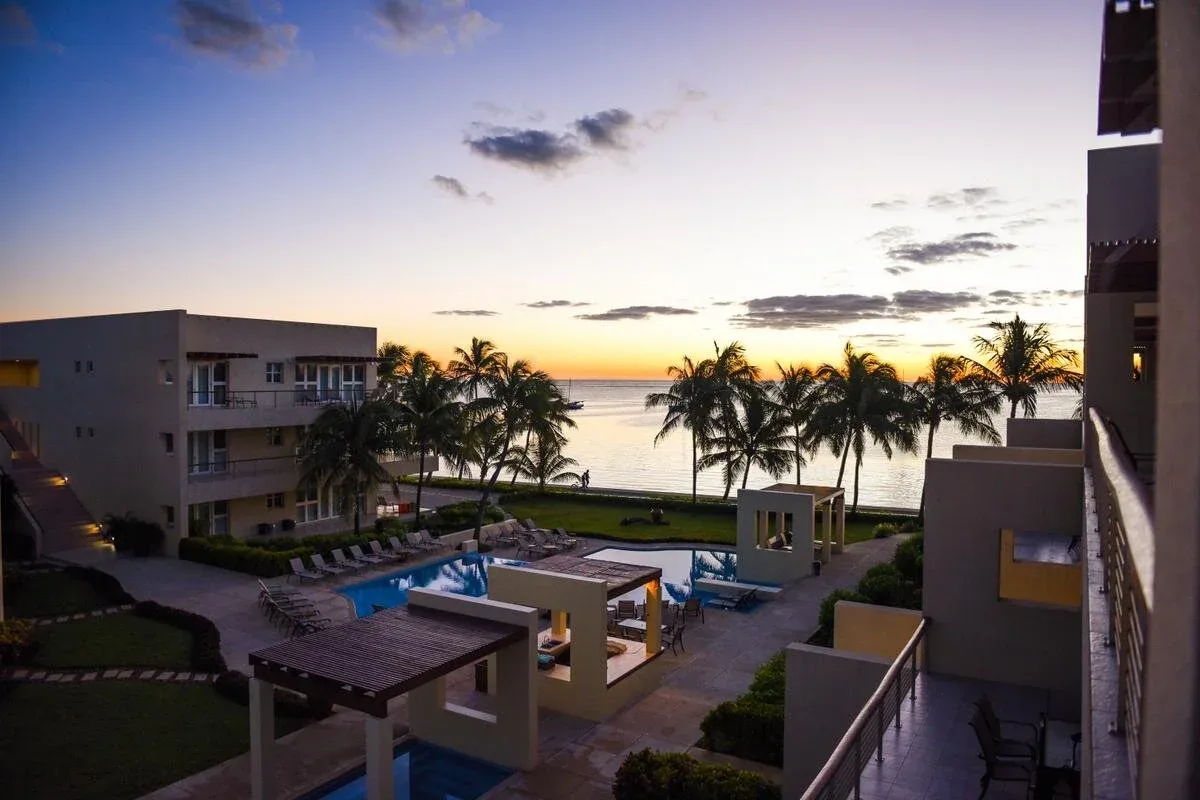 Espacio representativo del hotel: Una piscina y un patio del hotel dan a palmeras y al agua al atardecer.