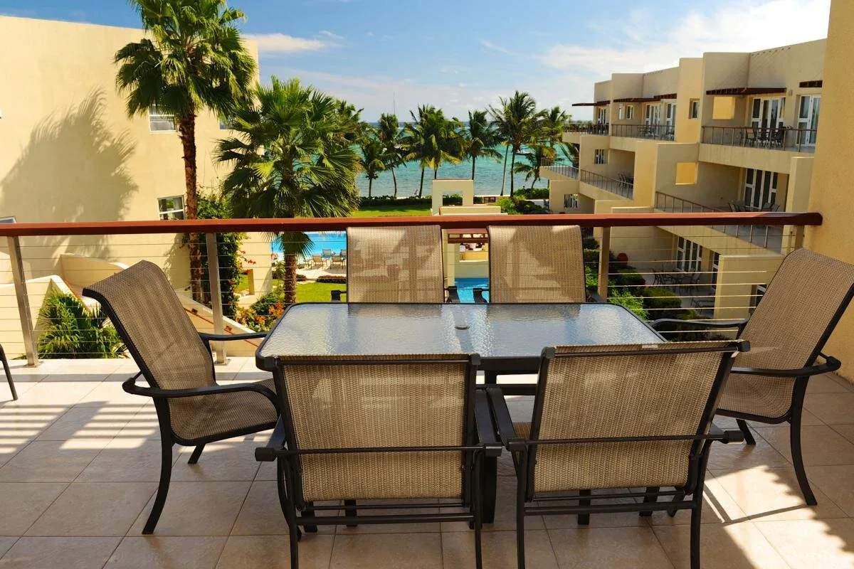 Espacio representativo del hotel: Una zona de estar en la terraza da a palmeras, edificios y el océano.