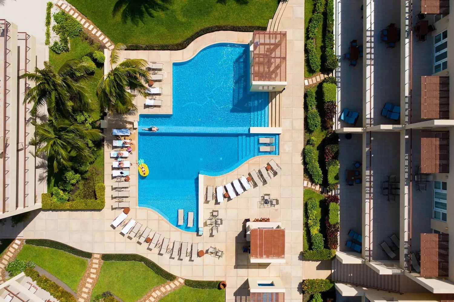 Espacio representativo del hotel: Vista aérea de una piscina rodeada de tumbonas y edificios.