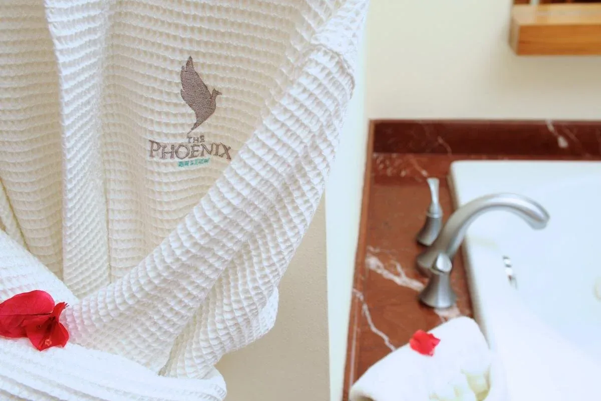 Espacio representativo del hotel: Una bata blanca cuelga junto a una bañera con un grifo curvo.