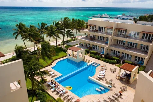 Espacio representativo del hotel: Una piscina junto al mar tiene palmeras y vistas al agua turquesa.
