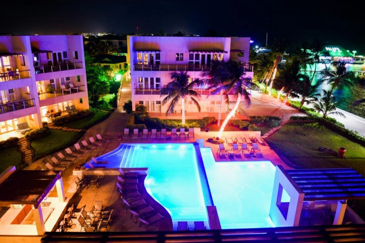 Espacio representativo del hotel: Una piscina exterior iluminada se encuentra entre edificios modernos por la noche.