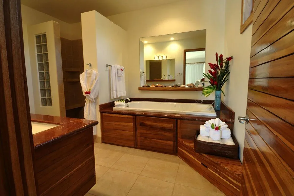 Espacio representativo del hotel: Un tocador de baño con un espejo amplio, gabinetes de madera y piso de baldosas.