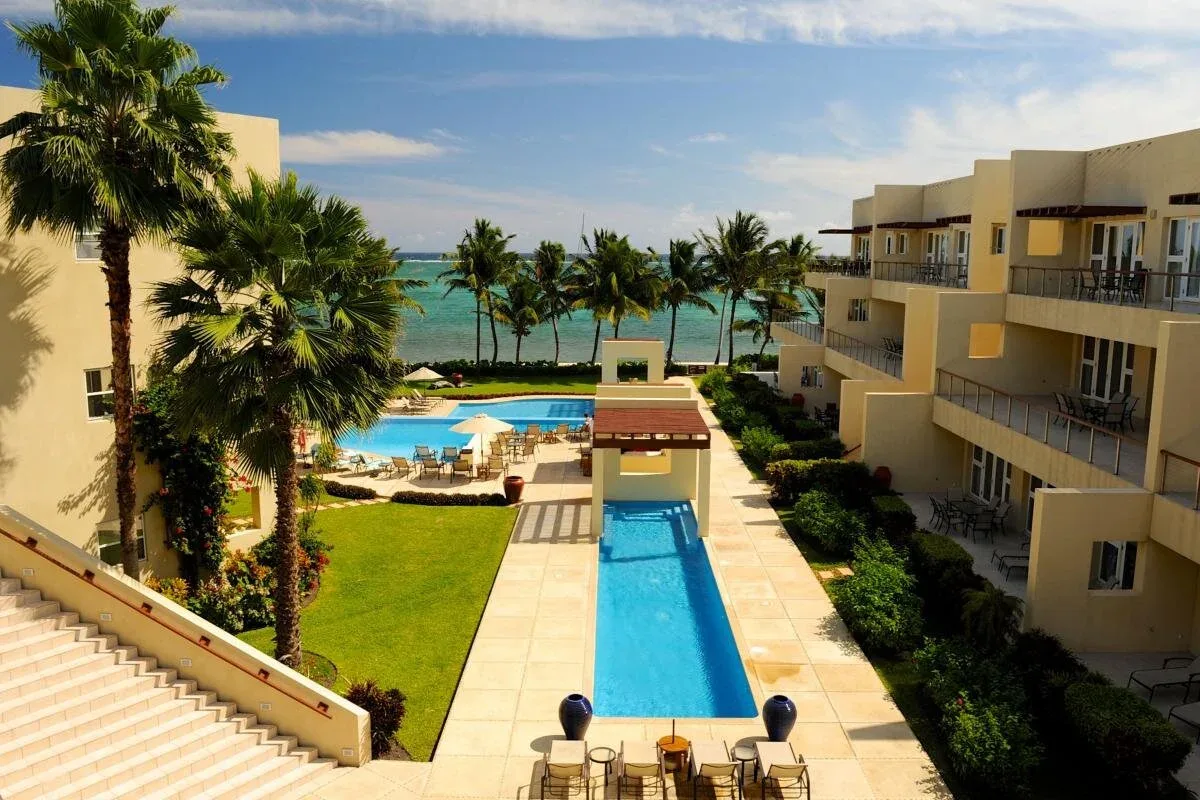 Espacio representativo del hotel: Un patio de resort con una piscina larga, palmeras y el mar al fondo.
