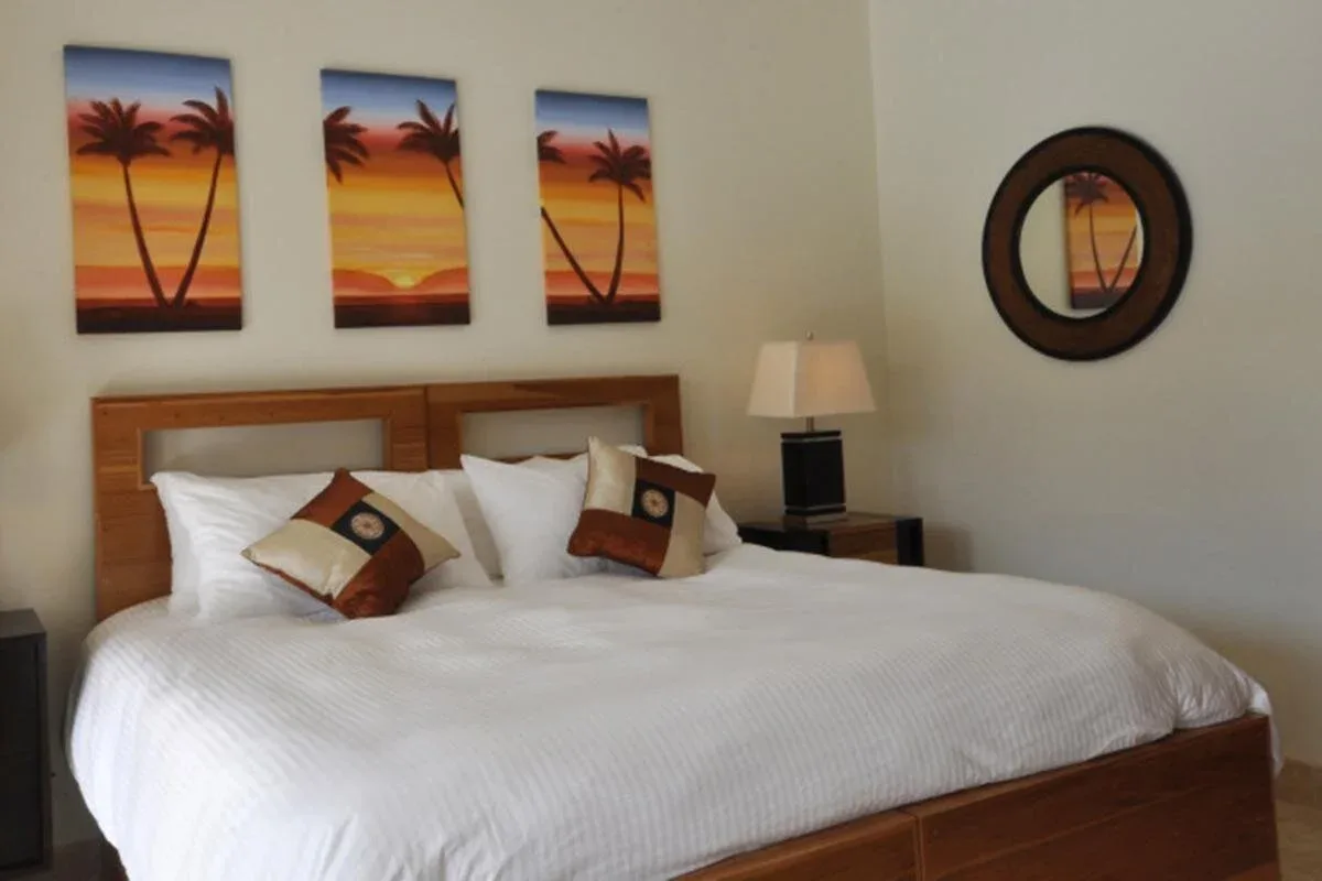 Espacio representativo del hotel: Dormitorio con una cama bien arreglada y cuadros de atardeceres.