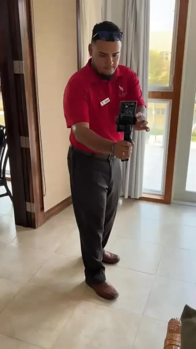Espacio representativo del hotel: Un hombre con camisa roja maneja una cámara sobre un trípode junto a una ventana.