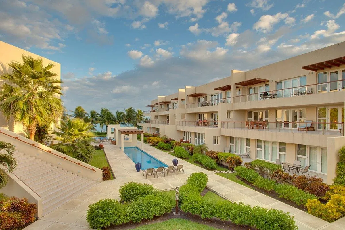 Espacio representativo del hotel: Un edificio hotelero da a una piscina exterior rodeada de vegetación tropical.