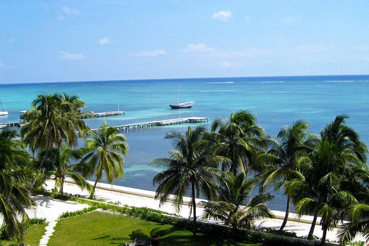 Espacio representativo del hotel: Una playa tropical con palmeras, agua turquesa y un barco mar adentro.