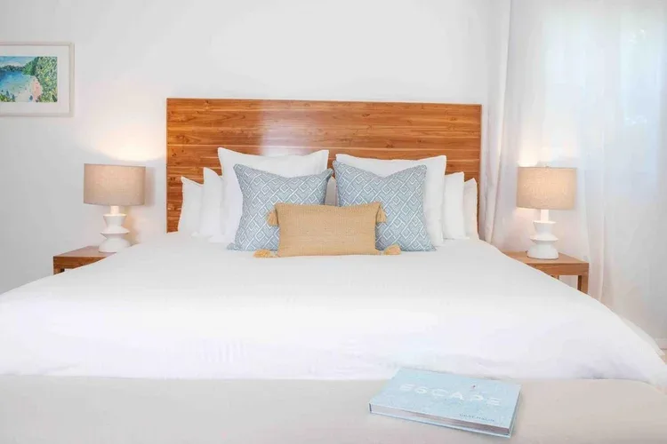 Espacio representativo del hotel: Un dormitorio con una cama bien tendida, cojines decorativos y lámparas de mesilla.