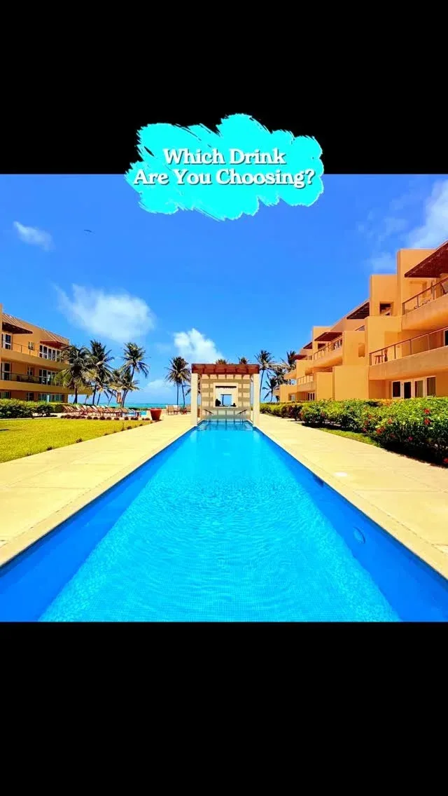 Espacio representativo del hotel: Una piscina de complejo turístico se extiende entre edificios naranjas bajo un cielo azul.