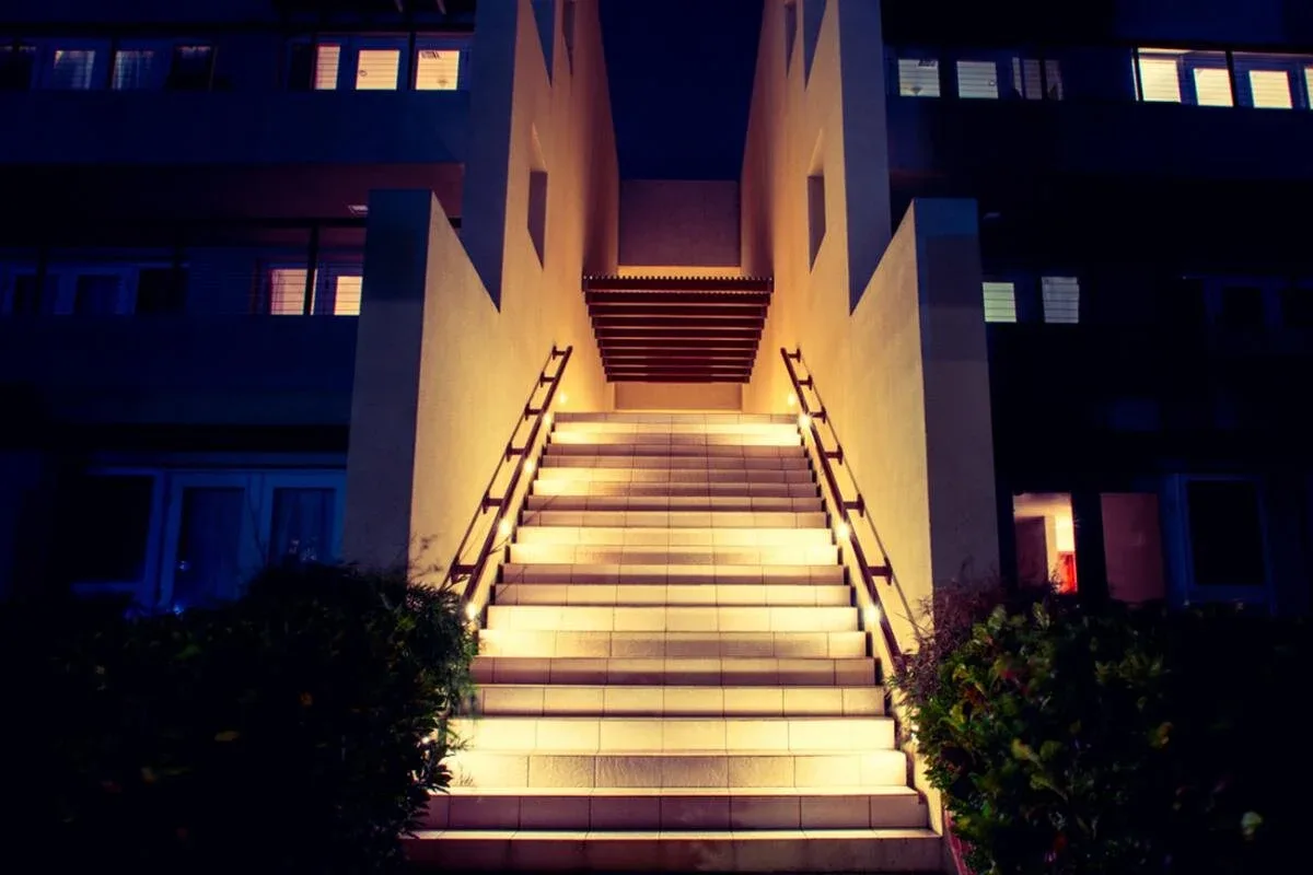 Espacio representativo del hotel: Una escalera exterior iluminada sube entre las alas oscuras del edificio.