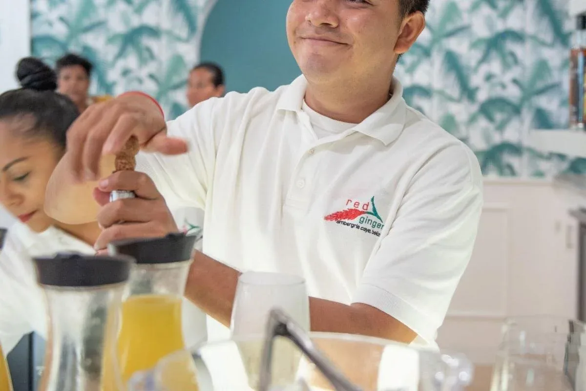 Espacio representativo del hotel: Una persona del personal prepara bebidas en un mostrador de una zona de servicio luminosa.