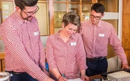 Representative hotel space: Three staff members in matching shirts gather around a table.